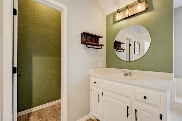 bathroom with vanity, vaulted ceiling, and hardwood / wood-style flooring