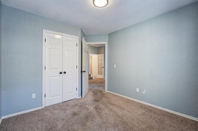 unfurnished bedroom featuring light carpet, a textured ceiling, and a closet