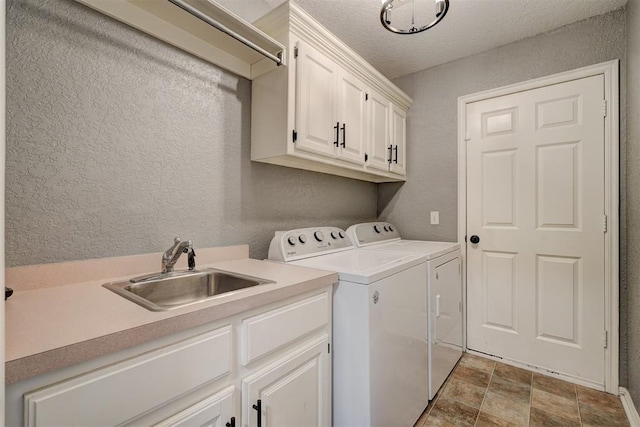 laundry area featuring separate washer and dryer, sink, cabinets, and a textured ceiling