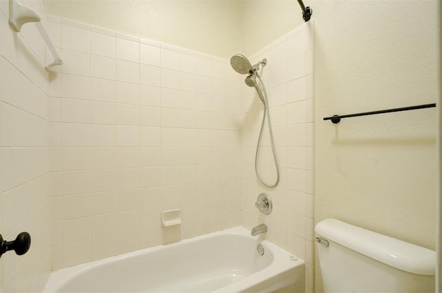 bathroom with toilet and tiled shower / bath