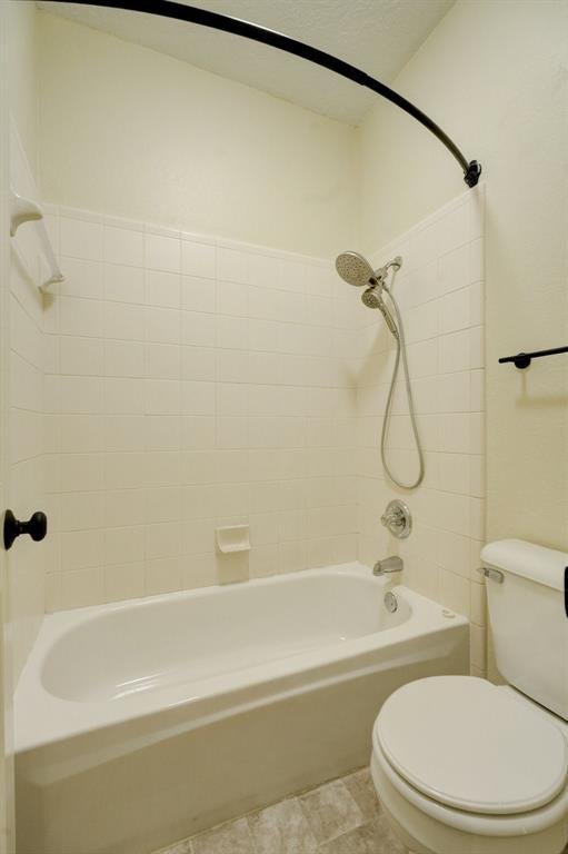 bathroom featuring toilet and tiled shower / bath