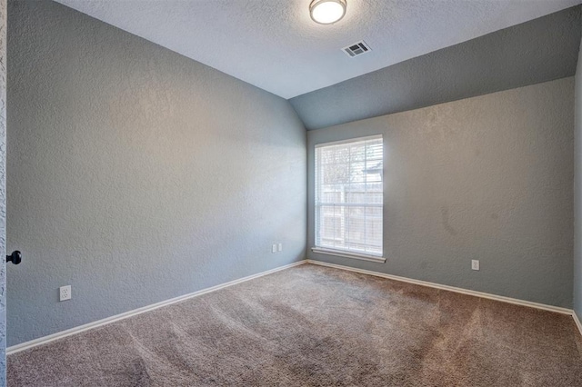 carpeted spare room with a textured ceiling and lofted ceiling