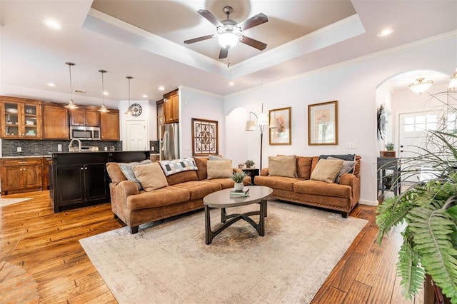 living room with a tray ceiling, light hardwood / wood-style floors, and ornamental molding