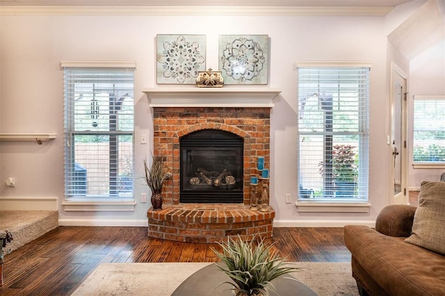 living room with dark hardwood / wood-style floors, a brick fireplace, plenty of natural light, and crown molding