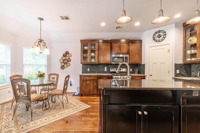 kitchen featuring dark stone counters, dark hardwood / wood-style floors, appliances with stainless steel finishes, and a chandelier