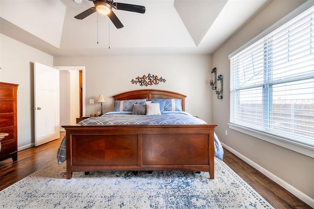 bedroom featuring ceiling fan, multiple windows, and a tray ceiling