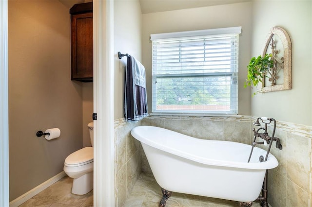 bathroom featuring tile patterned floors, toilet, a bathtub, and a healthy amount of sunlight