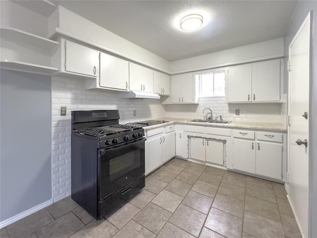 kitchen with light countertops, backsplash, white cabinets, black gas stove, and a sink