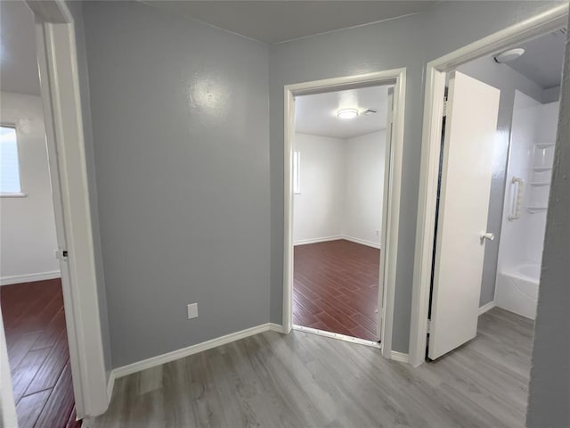 corridor with wood finished floors and baseboards