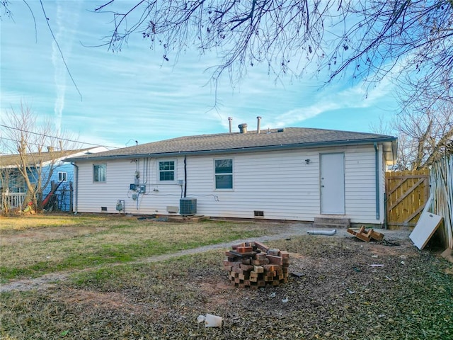 rear view of property featuring a lawn, an outdoor fire pit, crawl space, entry steps, and fence