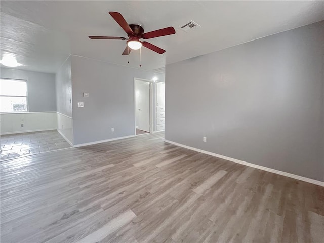 empty room featuring baseboards, visible vents, ceiling fan, and wood finished floors