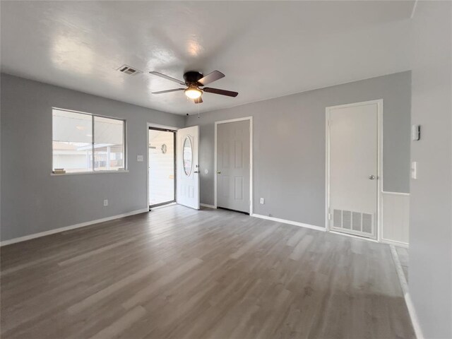 empty room featuring wood finished floors, visible vents, and baseboards