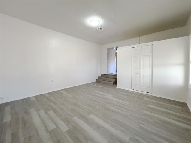 unfurnished bedroom featuring a closet, light wood-type flooring, visible vents, and baseboards