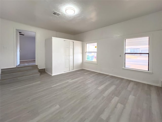 unfurnished bedroom featuring a closet, wood finished floors, visible vents, and baseboards