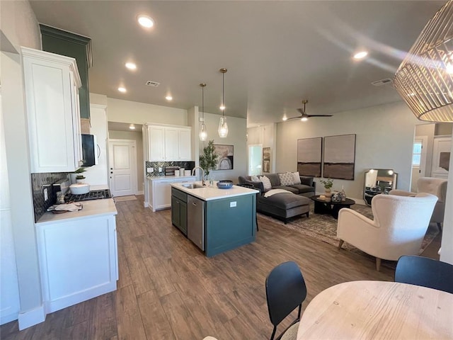 kitchen featuring white cabinetry, ceiling fan, hanging light fixtures, an island with sink, and decorative backsplash