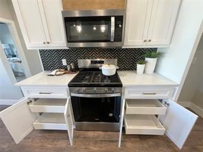 kitchen with decorative backsplash, white cabinets, stainless steel appliances, and dark hardwood / wood-style floors