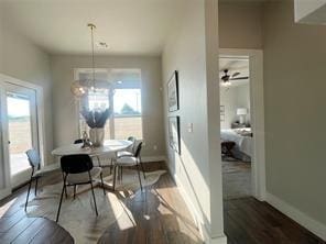 dining space featuring ceiling fan with notable chandelier and dark wood-type flooring