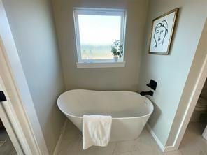 bathroom featuring a tub to relax in, tile patterned flooring, and toilet