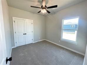 unfurnished bedroom with ceiling fan, dark carpet, and a closet