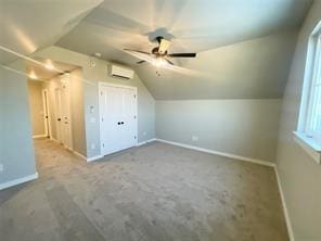 additional living space with a wall unit AC, ceiling fan, and vaulted ceiling