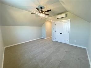 additional living space with carpet flooring, ceiling fan, lofted ceiling, and a wall unit AC