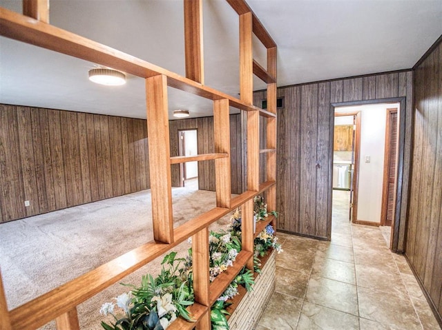 hall featuring light colored carpet and wooden walls