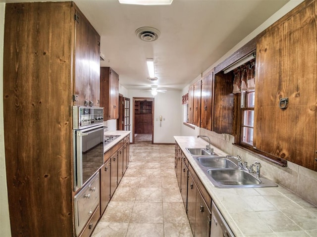 kitchen with tile counters, light tile patterned floors, appliances with stainless steel finishes, ceiling fan, and sink