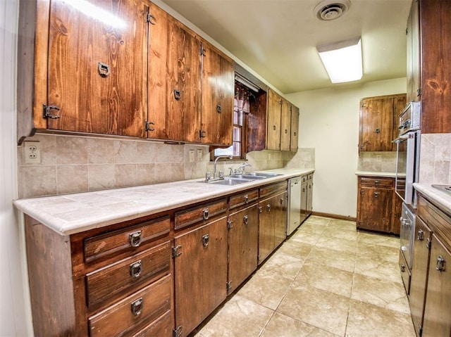 kitchen with sink, stainless steel appliances, tasteful backsplash, and light tile patterned floors