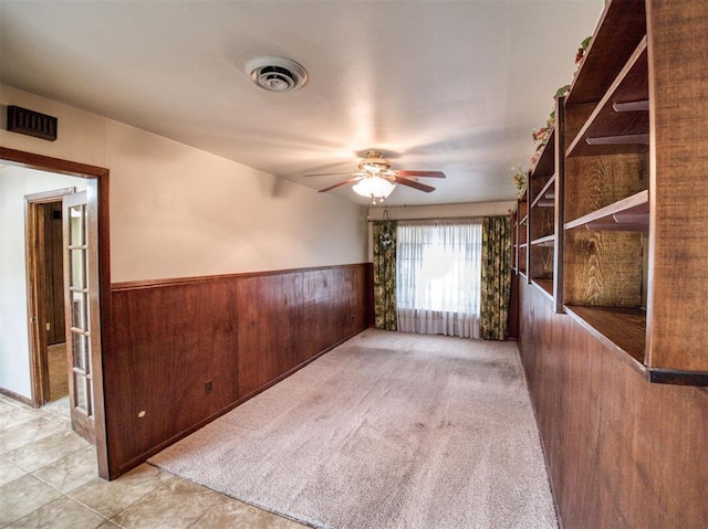 carpeted spare room with wood walls and ceiling fan