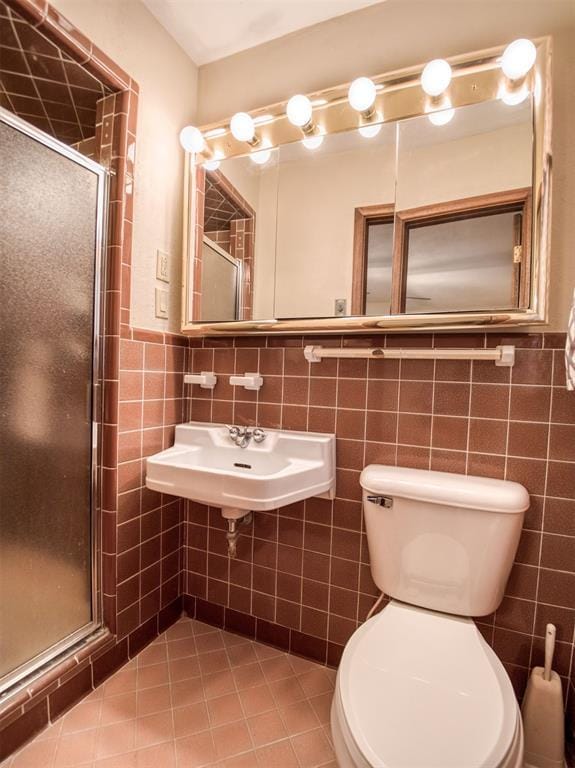 bathroom featuring toilet, tile walls, tile patterned floors, a shower with shower door, and sink