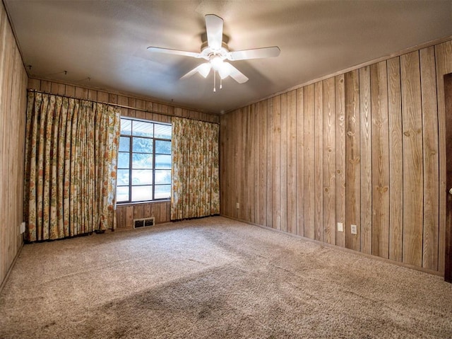 carpeted spare room featuring ceiling fan and wooden walls