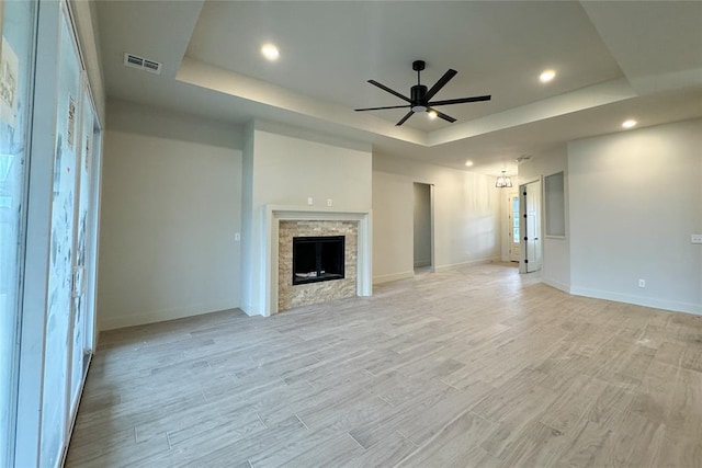9224 NW 83rd St, Yukon, OK 73099 - unfurnished living room with a raised ceiling, a ceiling fan, light wood-style flooring, baseboards, and a fireplace