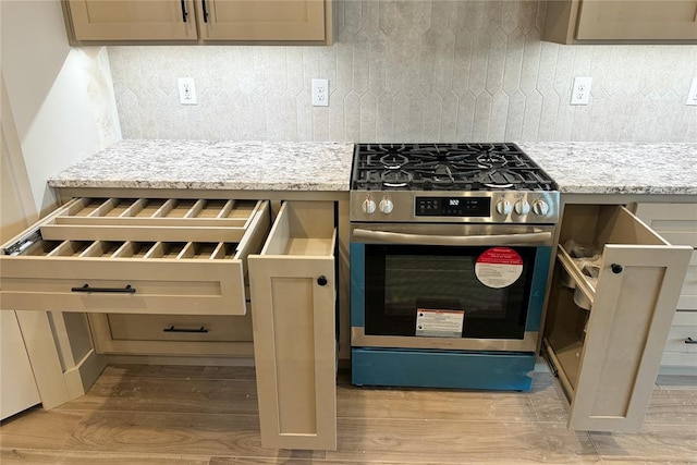 9224 NW 83rd St, Yukon, OK 73099 - kitchen featuring stainless steel gas stove, light wood-style flooring, backsplash, and light stone countertops