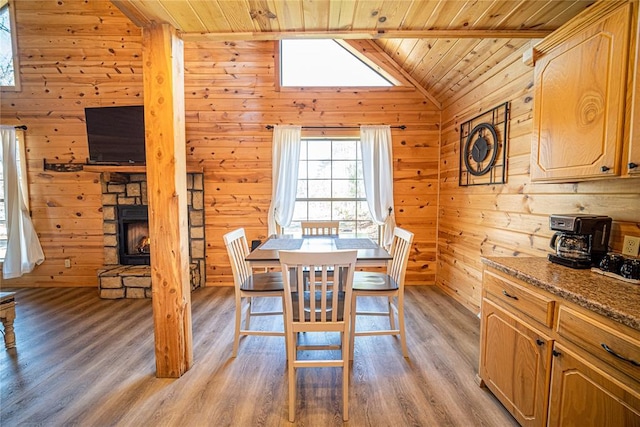 dining area featuring a fireplace, wood-type flooring, lofted ceiling, and wooden ceiling