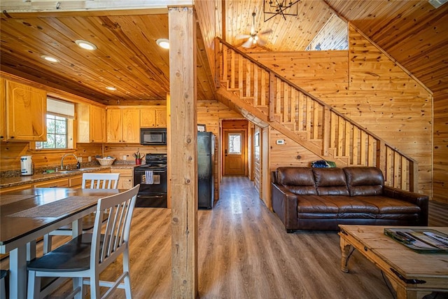 kitchen with wood walls, black appliances, sink, hardwood / wood-style flooring, and wood ceiling