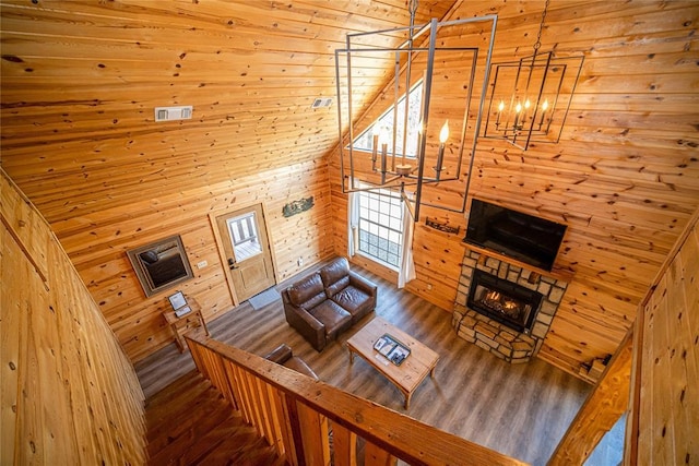 unfurnished living room featuring wooden walls, vaulted ceiling, and hardwood / wood-style flooring