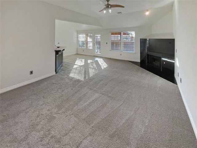 unfurnished living room featuring ceiling fan, light colored carpet, and lofted ceiling