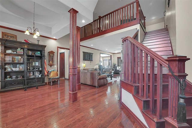 interior space featuring ornate columns, a towering ceiling, hardwood / wood-style floors, and an inviting chandelier