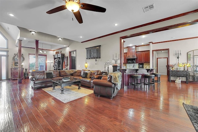 living room with crown molding, ceiling fan, dark hardwood / wood-style floors, and ornate columns