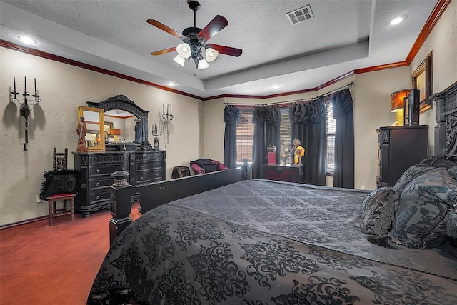 carpeted bedroom with a tray ceiling, ornamental molding, ceiling fan, and a textured ceiling