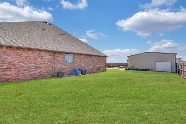 rear view of property featuring a garage, a lawn, an outdoor structure, and central AC