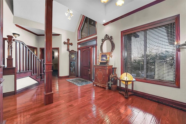 foyer with hardwood / wood-style flooring, a chandelier, vaulted ceiling, and ornate columns