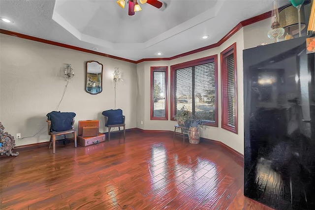 sitting room featuring hardwood / wood-style flooring, ornamental molding, ceiling fan, and a tray ceiling