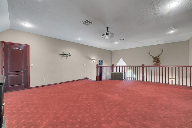 additional living space with vaulted ceiling, carpet, and a textured ceiling