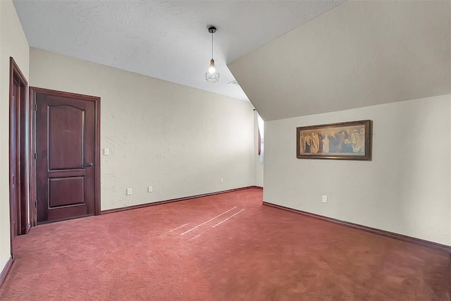 interior space featuring vaulted ceiling, carpet flooring, and a textured ceiling