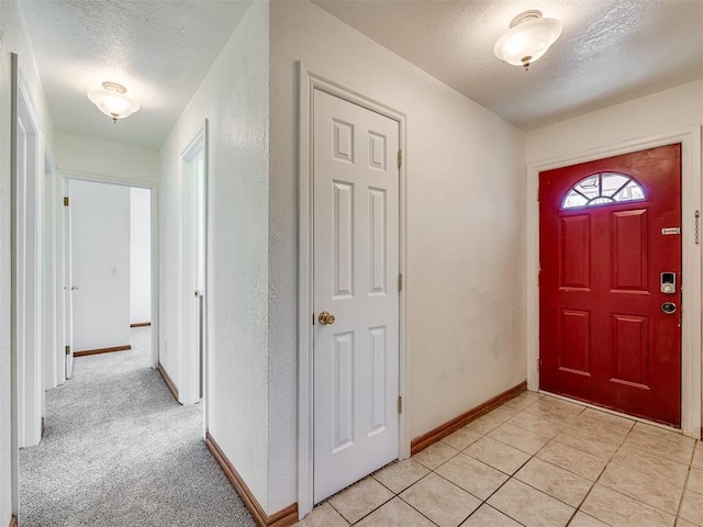 entrance foyer with a textured ceiling and light colored carpet