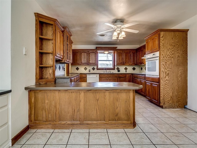 kitchen with decorative backsplash, white appliances, kitchen peninsula, and light tile patterned floors