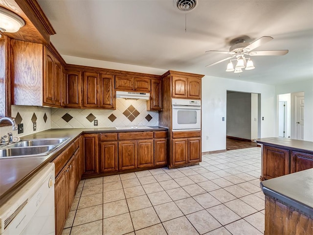 kitchen featuring white appliances, backsplash, sink, ceiling fan, and light tile patterned floors