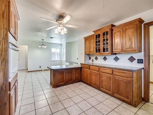 kitchen with backsplash, ceiling fan with notable chandelier, white oven, pendant lighting, and light tile patterned floors