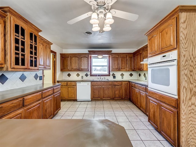 kitchen featuring ceiling fan, sink, tasteful backsplash, white appliances, and light tile patterned floors